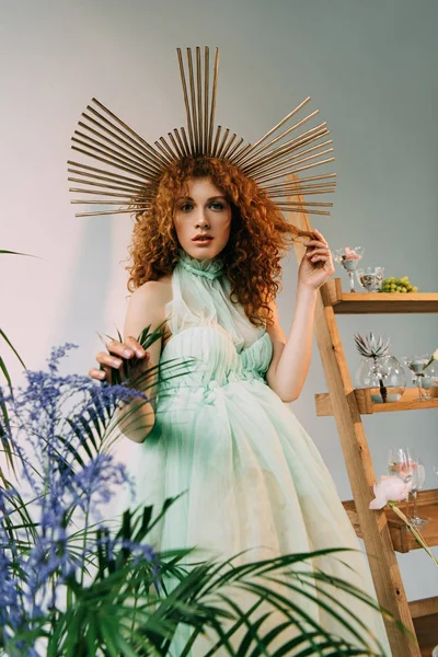 Menina ruiva elegante com acessório na cabeça posando perto de escada com flores e óculos — Fotografia de Stock