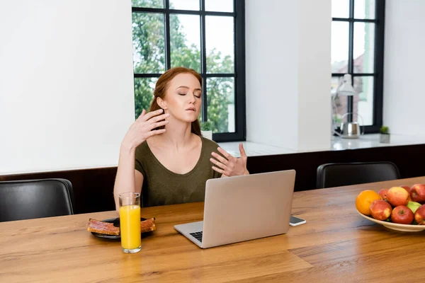 Freelancer suffering from heat near gadgets and breakfast on table — Stock Photo