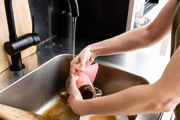 Vista cortada do copo de limpeza da mulher com pano na pia da cozinha — Fotografia de Stock