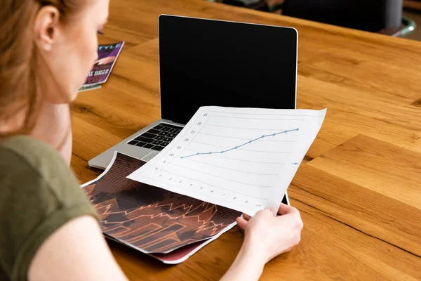 Выборочный фокус документа фрилансера с таблицей рядом с ноутбуком на столе — стоковое фото