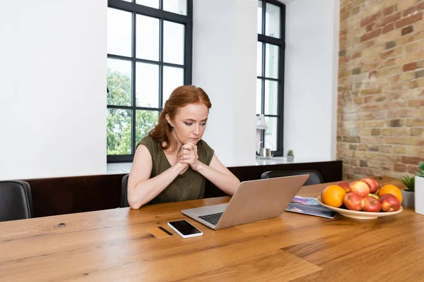 Mulher olhando para laptop perto de cartão de crédito, smartphone e frutas na mesa em casa — Fotografia de Stock