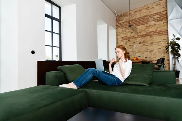 Freelancer suffering from heat while using laptop on couch — Stock Photo