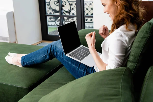 Enfoque selectivo del freelancer sonriente mostrando sí signo cerca de la computadora portátil en casa - foto de stock