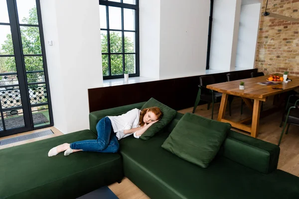 Mujer triste acostada en el sofá en la sala de estar - foto de stock