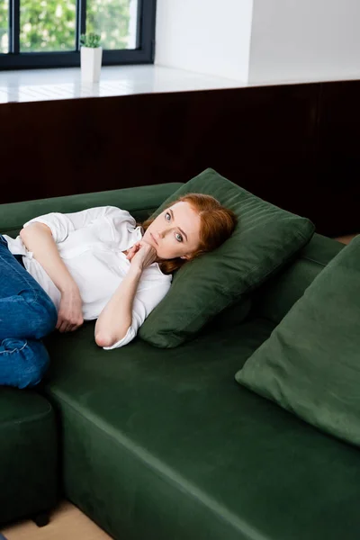 Разочарованная женщина смотрит в камеру, лежа дома на диване — стоковое фото