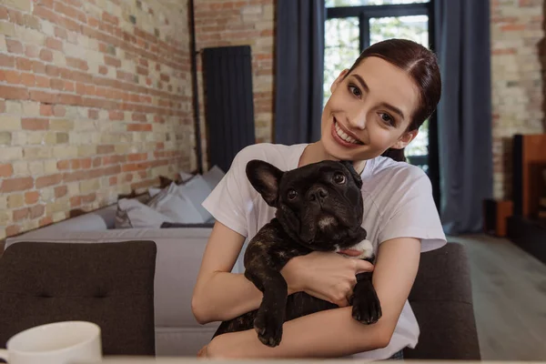 Smiling woman holding in arms cute french bulldog — Stock Photo