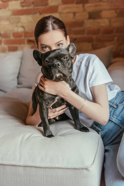 Young woman covering face near french bulldog while looking at camera — Stock Photo