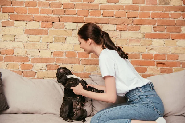 Feliz mujer jugando con lindo bulldog francés en sala de estar - foto de stock