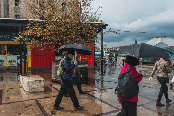 COPENHAGEN, DENMARK - APRIL 30, 2020: Selective focus of people walking with umbrellas on urban street during rain — Stock Photo