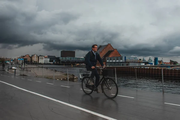 COPENHAGUE, DANEMARK - 30 AVRIL 2020 : Homme roulant à vélo dans une rue urbaine avec un ciel nuageux en arrière-plan — Photo de stock