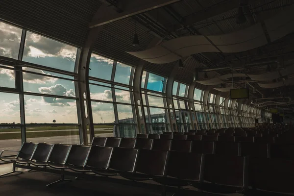 Sedie in sala d'attesa dell'aeroporto con cielo nuvoloso sullo sfondo — Foto stock