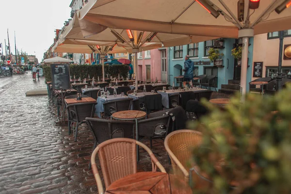 Selective focus of tables and chairs under umbrellas on urban street, Copenhagen, Denmark — Stock Photo