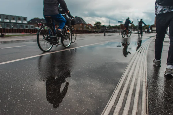Selective focus of people walking and riding bicycles on urban street during rain in Copenhagen, Denmark — Stock Photo