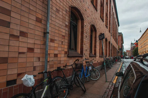 Bicicletas cerca de la fachada del edificio en la pasarela en la calle urbana en Copenhague, Dinamarca - foto de stock