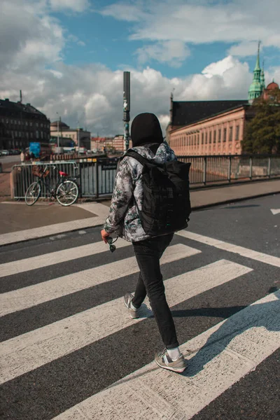 Vista trasera del hombre caminando en la encrucijada en la calle soleada en Copenhague, Dinamarca - foto de stock