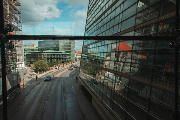 COPENHAGEN, DINAMARCA - 30 DE ABRIL DE 2020: Fachada de la Biblioteca Real Diamante Negro con carretera y cielo nublado al fondo - foto de stock