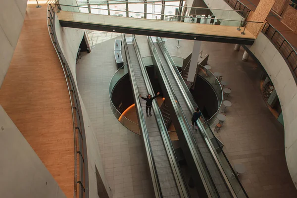 COPENHAGEN, DENMARK - APRIL 30, 2020: High angle view of cheerful man on escalator in Black Diamond Royal Library, Copenhagen, Denmark — Stock Photo