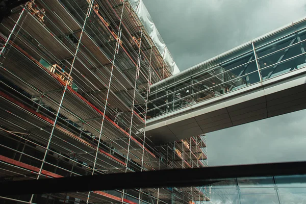 Niedriger Blickwinkel auf die Baukonstruktion mit Glaskorridor und bewölktem Himmel im Hintergrund in Kopenhagen, Dänemark — Stockfoto