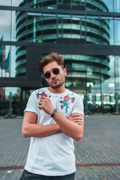 Giovane uomo in occhiali da sole guardando la macchina fotografica sulla strada urbana con edificio sullo sfondo a Copenaghen, Danimarca — Foto stock