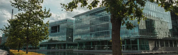 Panoramic shot of trees and glass facade of building near canal, Copenhagen, Denmark — Stock Photo
