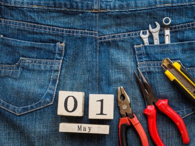 ahşap blok Takvim 1 Mayıs ve Sanayi araçlar jean doku arka plan üzerinde. İşçi Bayramı kavramı.
