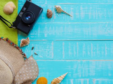 Plaj aksesuarları, şapka beach de dahil olmak üzere deniz hayvanı kabuğu, havlu ve retro kamera üzerinde parlak mavi yaz tatil ve tatil kavramı için ahşap arka plan.