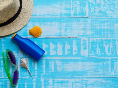 Güneş gözlüğü, Güneş kremi, şapka plaj, kabuk üzerinde parlak da dahil olmak üzere plaj aksesuarları yaz tatil ve tatil kavramı için ahşap arka plan mavi.