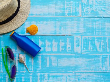 Güneş gözlüğü, Güneş kremi, şapka plaj, kabuk üzerinde parlak da dahil olmak üzere plaj aksesuarları yaz tatil ve tatil kavramı için ahşap arka plan mavi.