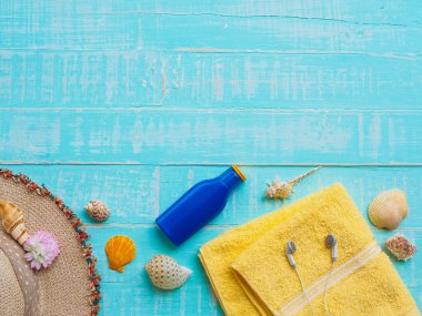 Plaj aksesuarları dahil olmak üzere güneş koruyucu, şapka plaj, kabuk, mavi sarı Havlu ve kulaklık üzerinde parlak pastel ahşap arka plan yaz tatil ve tatil konsepti için.