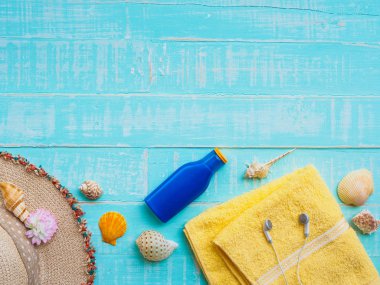 Plaj aksesuarları dahil olmak üzere güneş koruyucu, şapka plaj, kabuk, mavi sarı Havlu ve kulaklık üzerinde parlak pastel ahşap arka plan yaz tatil ve tatil konsepti için.