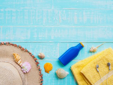 Plaj aksesuarları dahil olmak üzere güneş koruyucu, şapka plaj, kabuk, mavi sarı Havlu ve kulaklık üzerinde parlak pastel ahşap arka plan yaz tatil ve tatil konsepti için.