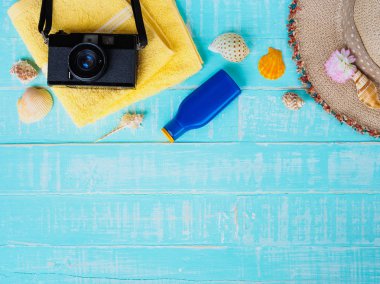 Plaj aksesuarları dahil olmak üzere güneş koruyucu, şapka plaj, kabuk, mavi sarı Havlu ve retro kamera önünde parlak pastel ahşap arka plan yaz tatil ve tatil konsepti için.