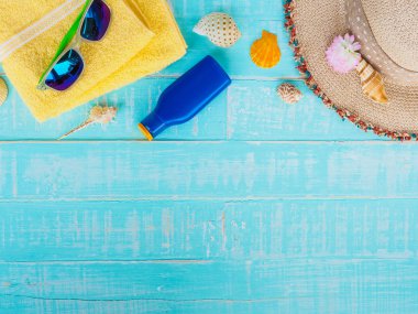 Plaj aksesuarları dahil olmak üzere güneş koruyucu, şapka plaj, kabuk, mavi sarı Havlu ve retro kamera önünde parlak pastel ahşap arka plan yaz tatil ve tatil konsepti için.