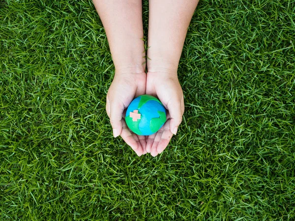 earth day. earth in hands and green grass field background. environment save earth concept.