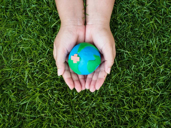 Dünya günü. dünya el ve yeşil çim alan arka plan. çevre dünya kavramı kaydetmek.