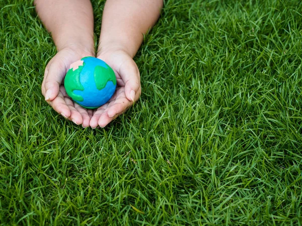 Dünya günü. dünya el ve yeşil çim alan arka plan. çevre dünya kavramı kaydetmek.