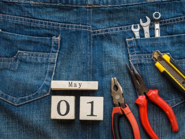 ahşap blok Takvim 1 Mayıs ve Sanayi araçlar jean doku arka plan üzerinde. İşçi Bayramı kavramı.