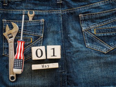 ahşap blok Takvim 1 Mayıs ve Sanayi araçlar jean doku arka plan üzerinde. İşçi Bayramı kavramı.
