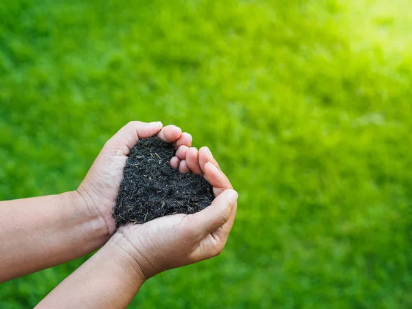 Eart day, save the earth, love concept. the woman hand holding a soil on green grass blur background.