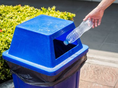 Yakın plan kadın eli boş plastik su şişesini geri dönüşüm kutusuna atıyor..