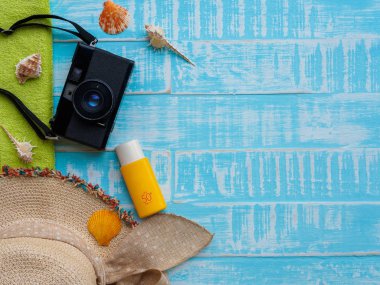 Plaj aksesuarları, Güneş kremi de dahil olmak üzere Mavi şapka beach, kabuk ve retro kamera önünde parlak pastel ahşap arka plan için yaz tatil ve tatil kavramı.