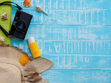 Plaj aksesuarları, Güneş kremi de dahil olmak üzere Mavi şapka beach, kabuk ve retro kamera önünde parlak pastel ahşap arka plan için yaz tatil ve tatil kavramı.