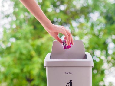 El trowing bir kağıt bokeh arka plan üzerinde bir çöp kutusu içine. temizlik kavramı.