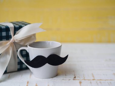 Mutlu babalar günü kavramı. hediye kutusu, bir fincan kahve beyaz ve sarı zemin üzerine bıyıklı.