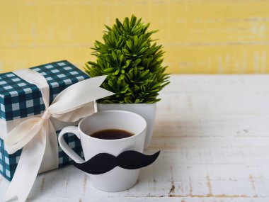 Mutlu babalar günü kavramı. hediye kutusu, bir fincan kahve beyaz ve sarı zemin üzerine bıyıklı.