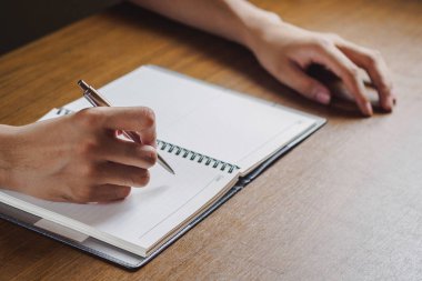 Adamın el ahşap masaüstüne yerleştirdiğiniz not defterinde yazılı kapatın. iş, eğitim kavramı.