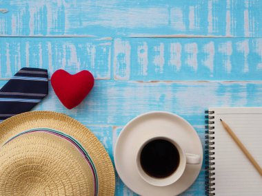 Mutlu babalar günü ile bir fincan kahve, redheart, şapka, kravat, Not defteri ve kalem mavi ahşap arka plan üzerinde yazıt. Babalar günü kavramı.