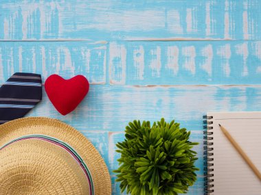 Mutlu babalar günü yazıt ile bitki, redheart, şapka, kravat, Not defteri ve kalem mavi ahşap zemin üzerinde. Babalar günü kavramı.