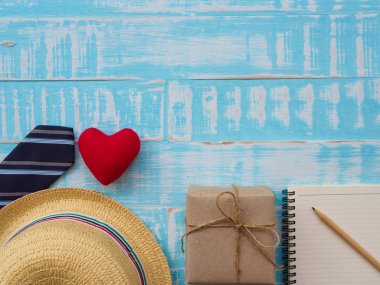 Mutlu babalar günü yazıt hediye kutusu, redheart, şapka, kravat, Not defteri ve kalem mavi ahşap zemin üzerinde. Babalar günü kavramı.