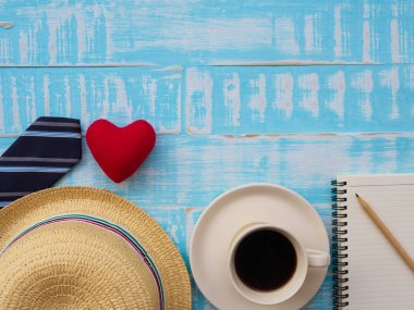 Mutlu babalar günü ile bir fincan kahve, redheart, şapka, kravat, Not defteri ve kalem mavi ahşap arka plan üzerinde yazıt. Babalar günü kavramı.
